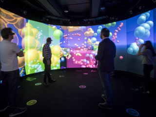 People standing in front of illuminated wraparound interactive screen